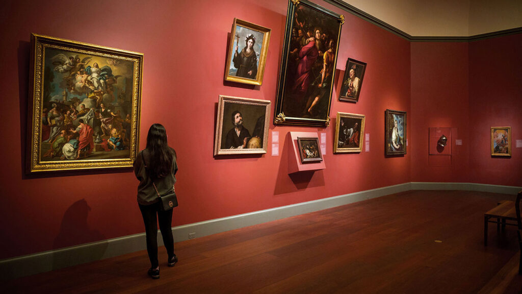 A visitor viewing paintings in a European gallery