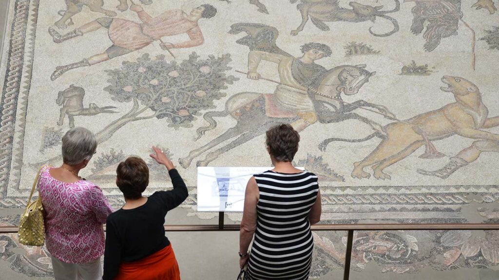 Three visitors viewing 'Worcester Hunt Floor Mosaic'