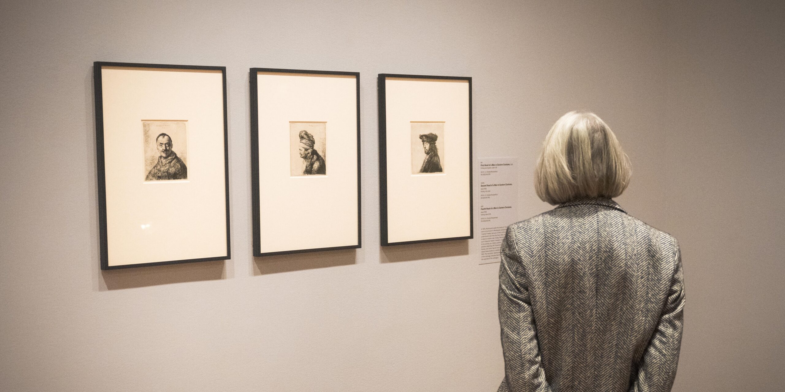 A guest viewing three works in the 'Rembrandt' exhibition