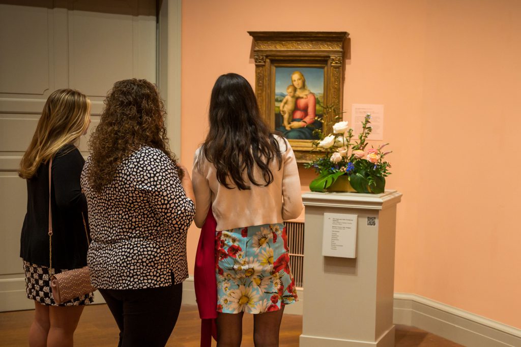 Guests viewing a floral arrangement in a gallery