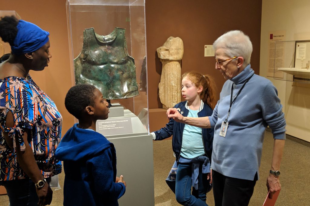 A docent talks to guests about Greek art