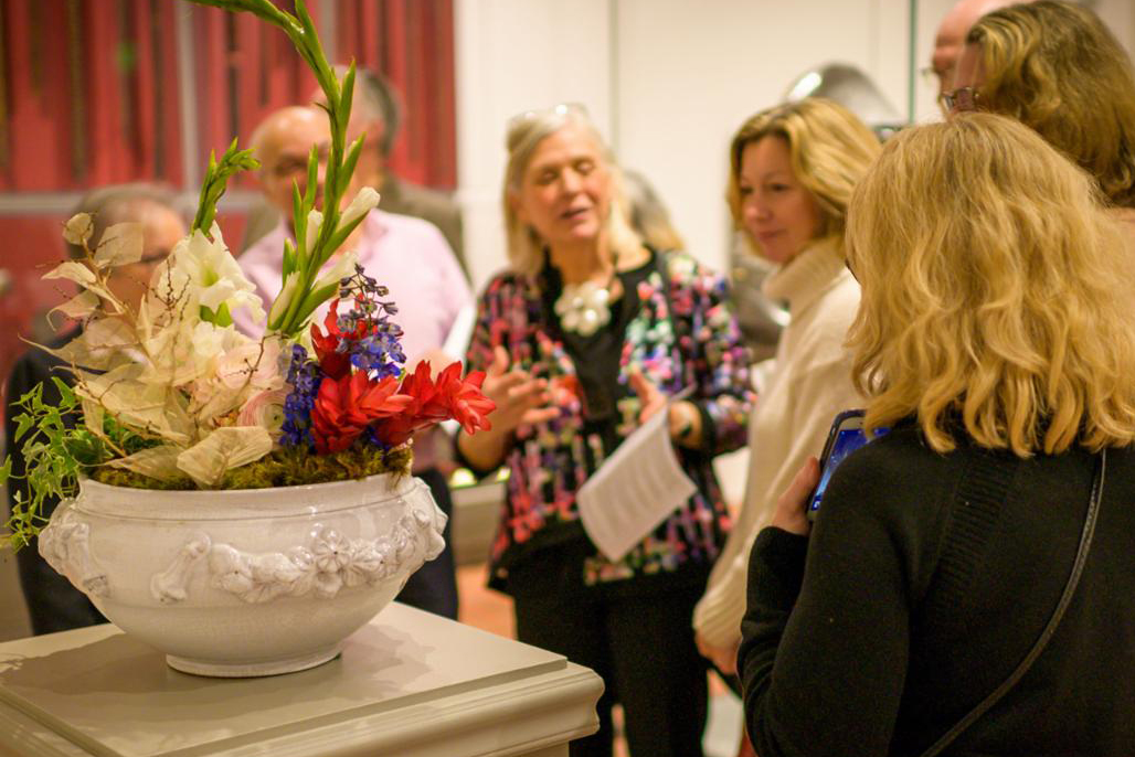 A docent talks to a tour group about a floral interpretation of an artwork