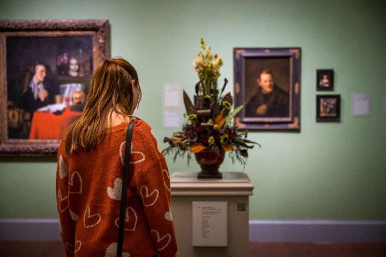 A guest viewing a floral arrangement in a gallery