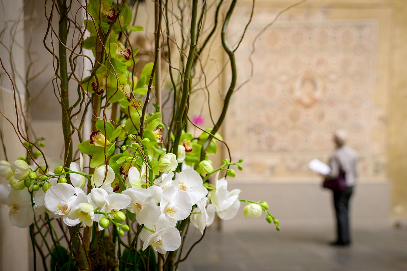 Close-up view of a floral arrangement in Renaissance Court with a visitor far in the background