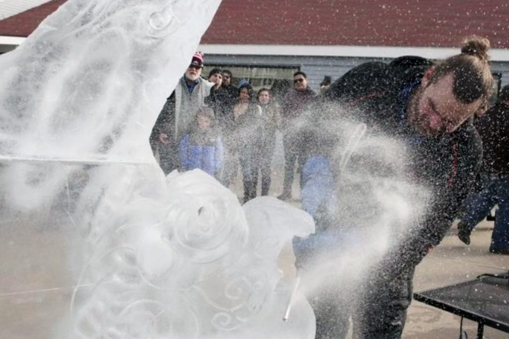 Donald Chapelle of Brilliant Ice working on an ice sculpture with a crowd watching in the background