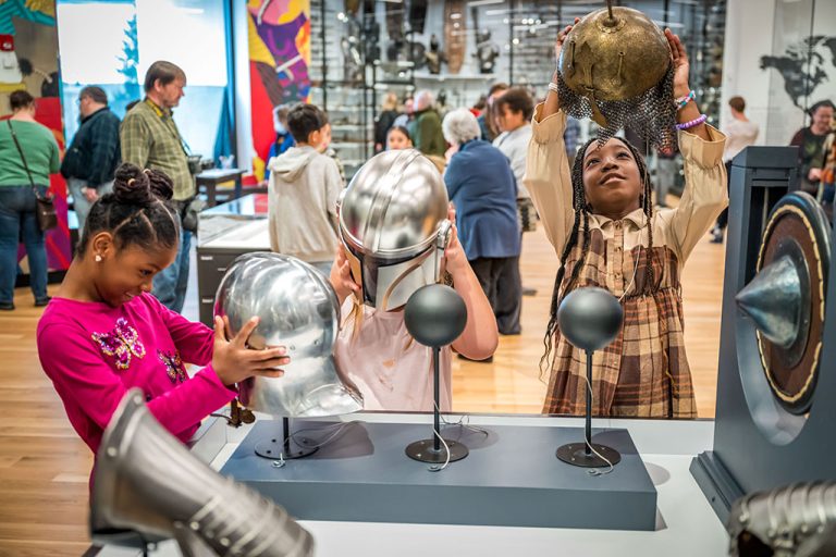 Two young visitors try on different types of helmet