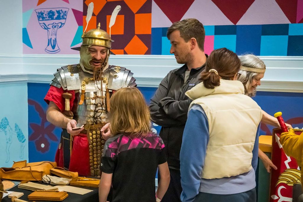A Roman Legion reenactor educates a group of visitors about the Roman military through objects on display