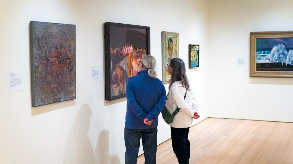 Two visitors standing together viewing artworks in the Modern Art gallery