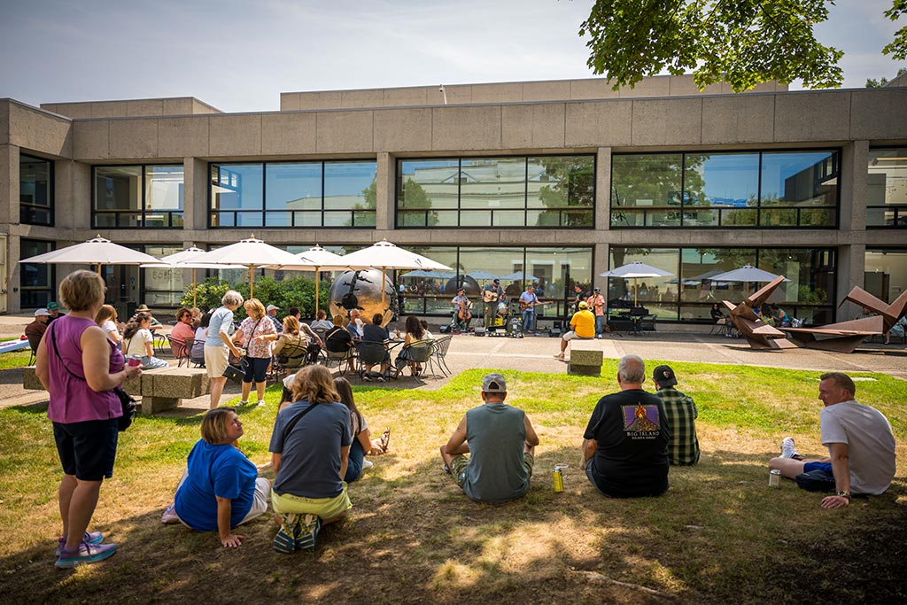 Visitors enjoying a summer afternoon of drinks and live music in the Stoddard Garden Courtyard